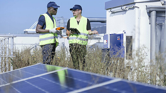 Two Leadec employees on factory roof with photovoltaic panels.
