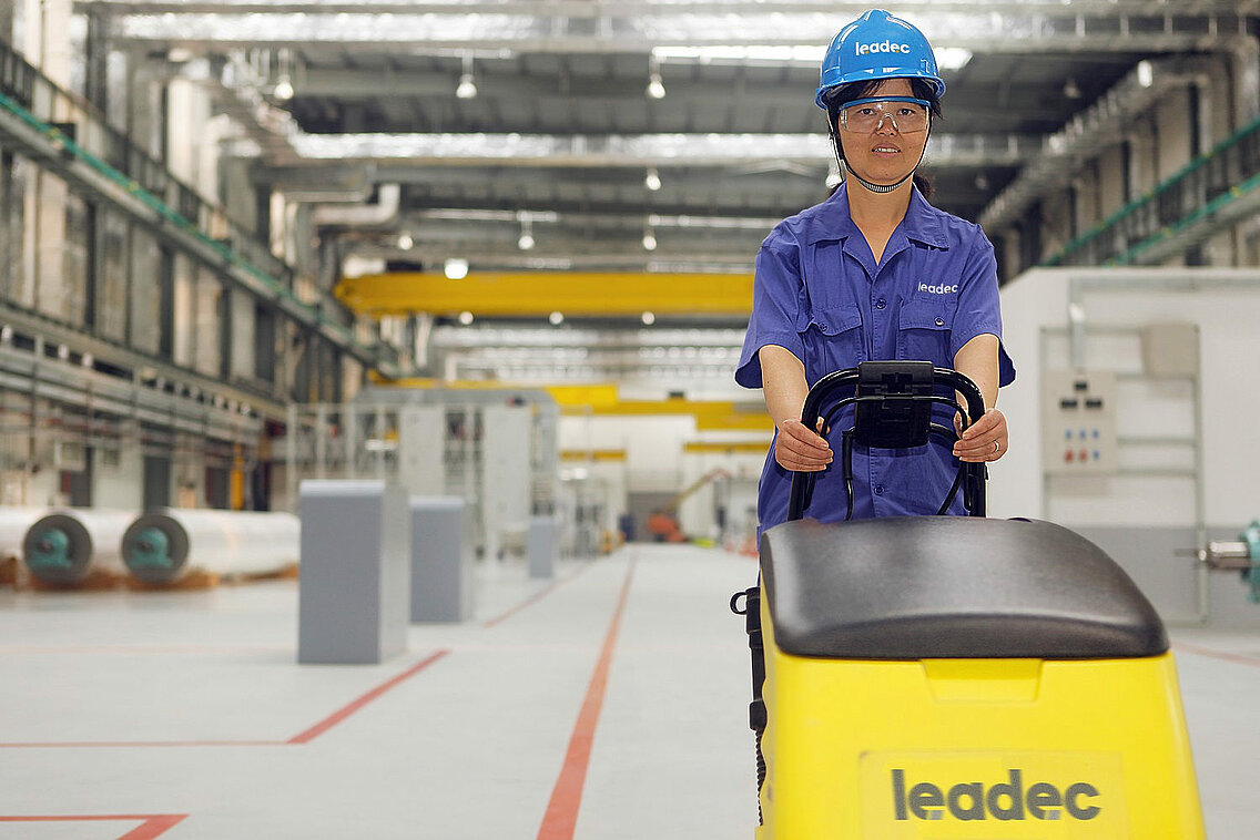 Female Leadec employee with lifting truck on shopfloor. 