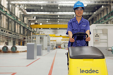 Female Leadec employee with lifting truck on shopfloor. 