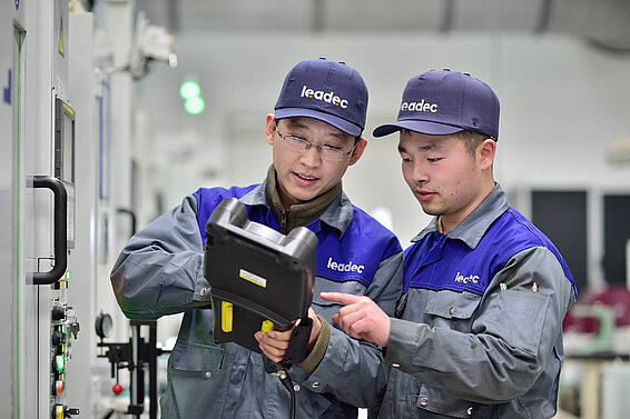 Two Leadec employees checking data on a tablet. 