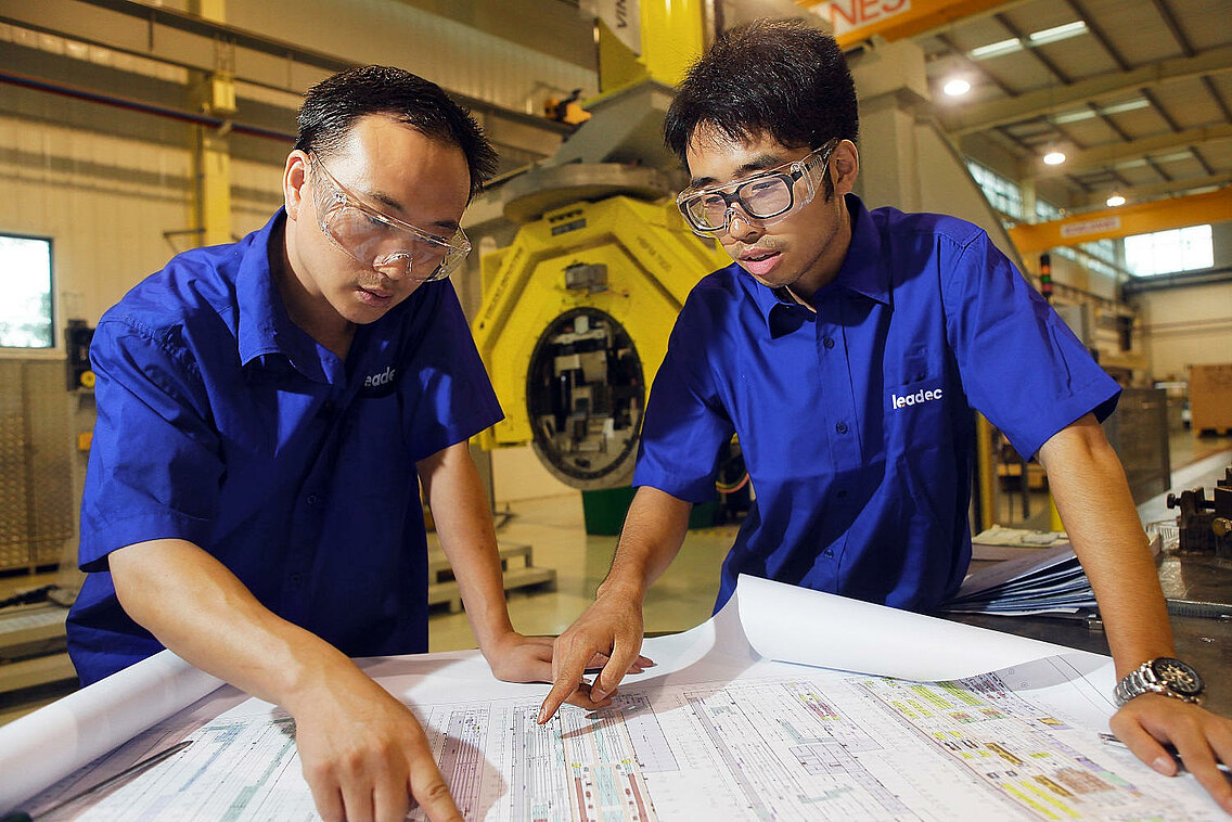Two Leadec employees with plan for relocation of production line.
