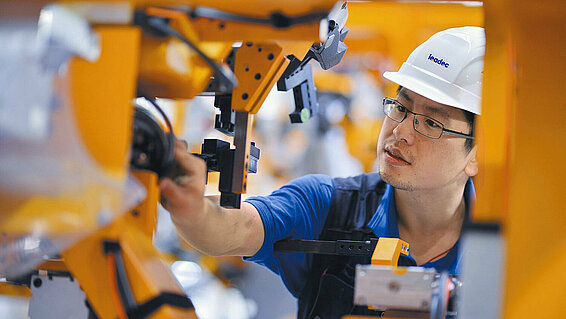 Leadec employee makes adjustments to robot arm.